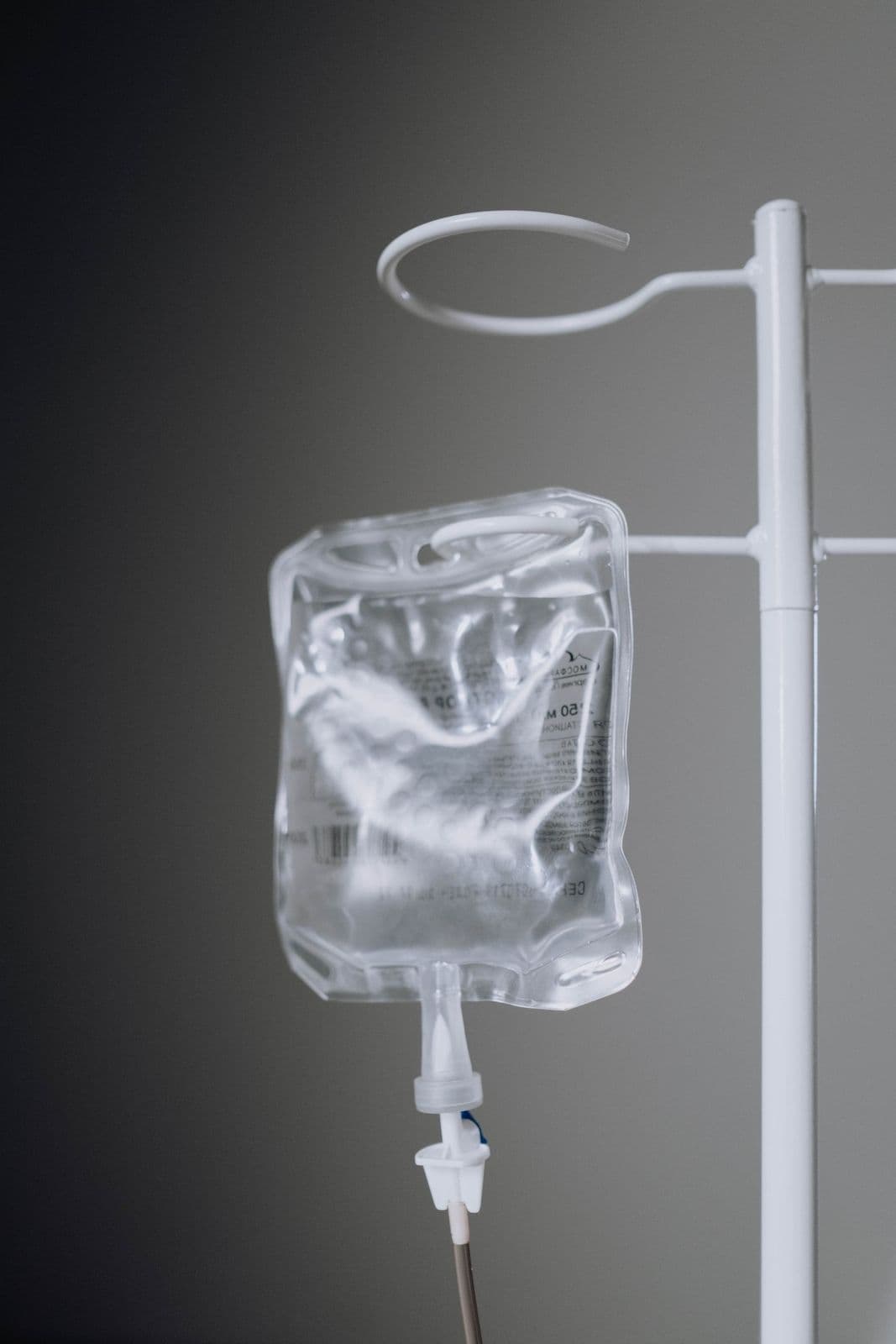Bolsa de soro pendurada em suporte de infusão com equipo, em ambiente clínico