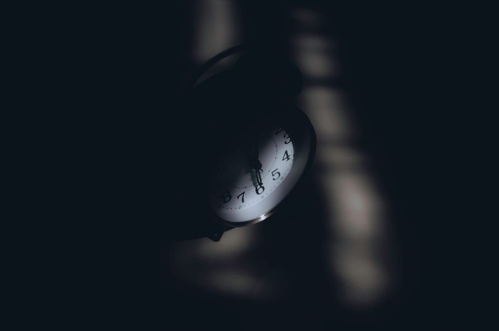 Despertador sobre o criado-mudo na madrugada, com luz vinda da janela