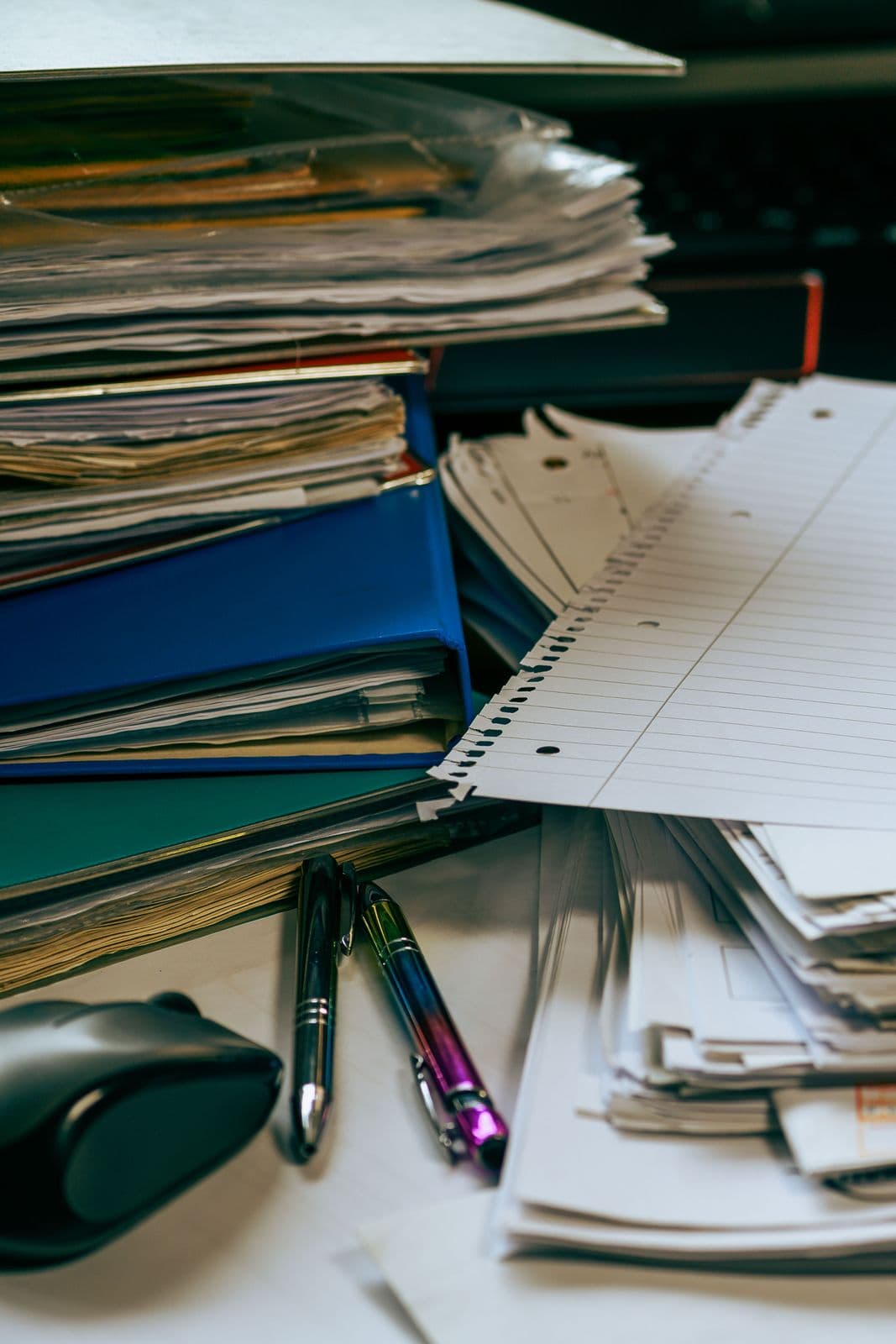 Pilha de pastas e documentos com canetas sobre a mesa de escritório