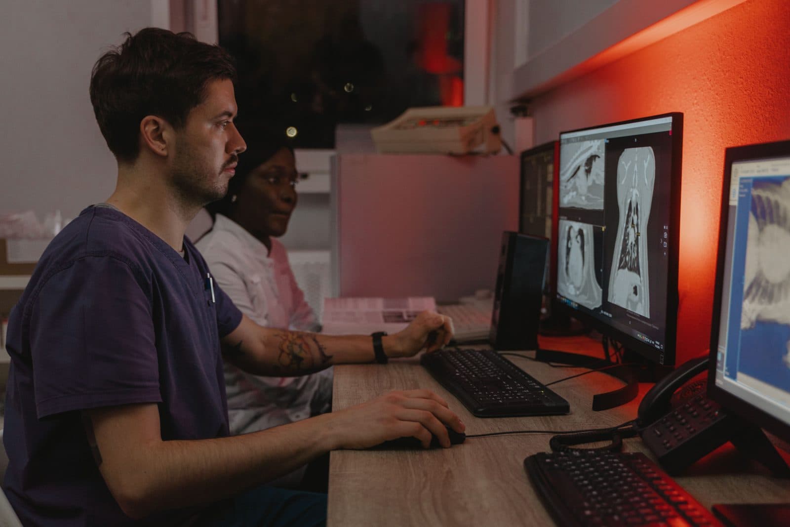 Equipe médica analisando imagens de tomografia em monitores na sala de laudos