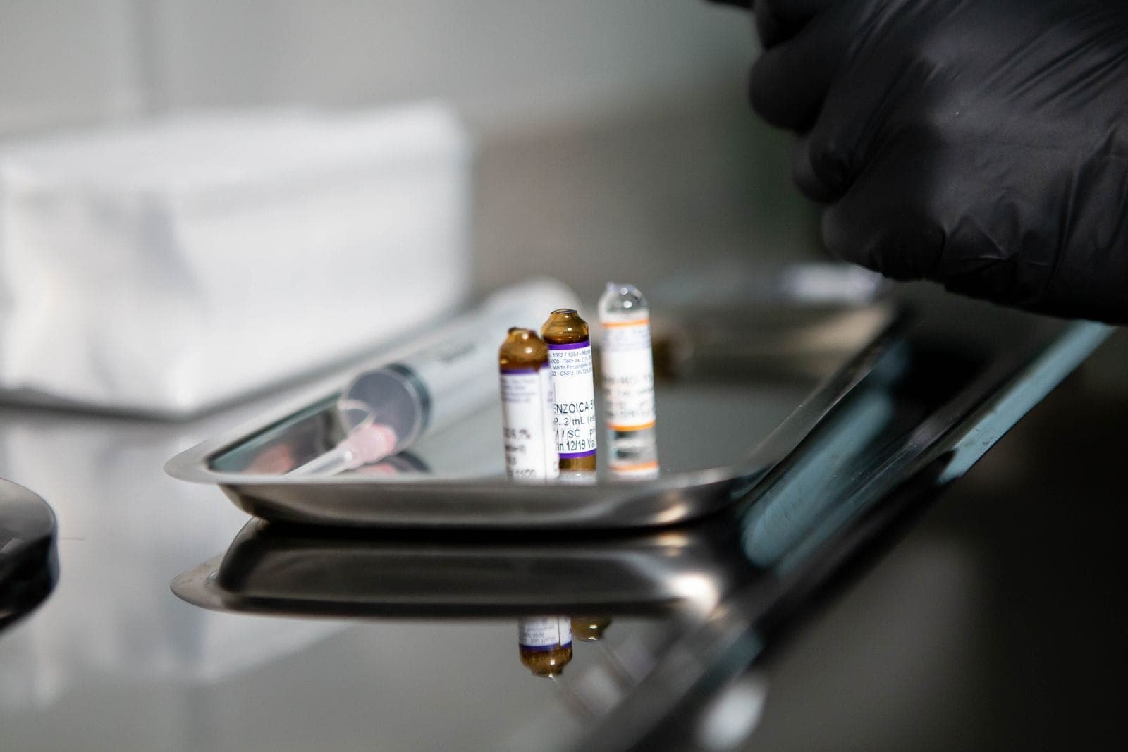 Ampolas de medicação e seringa preparadas em bandeja de inox