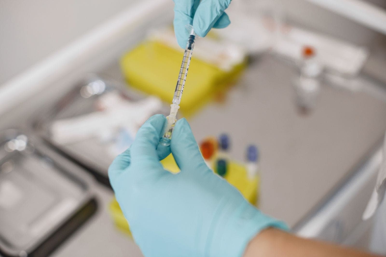 Profissional de saúde preparando uma seringa a partir de uma ampola