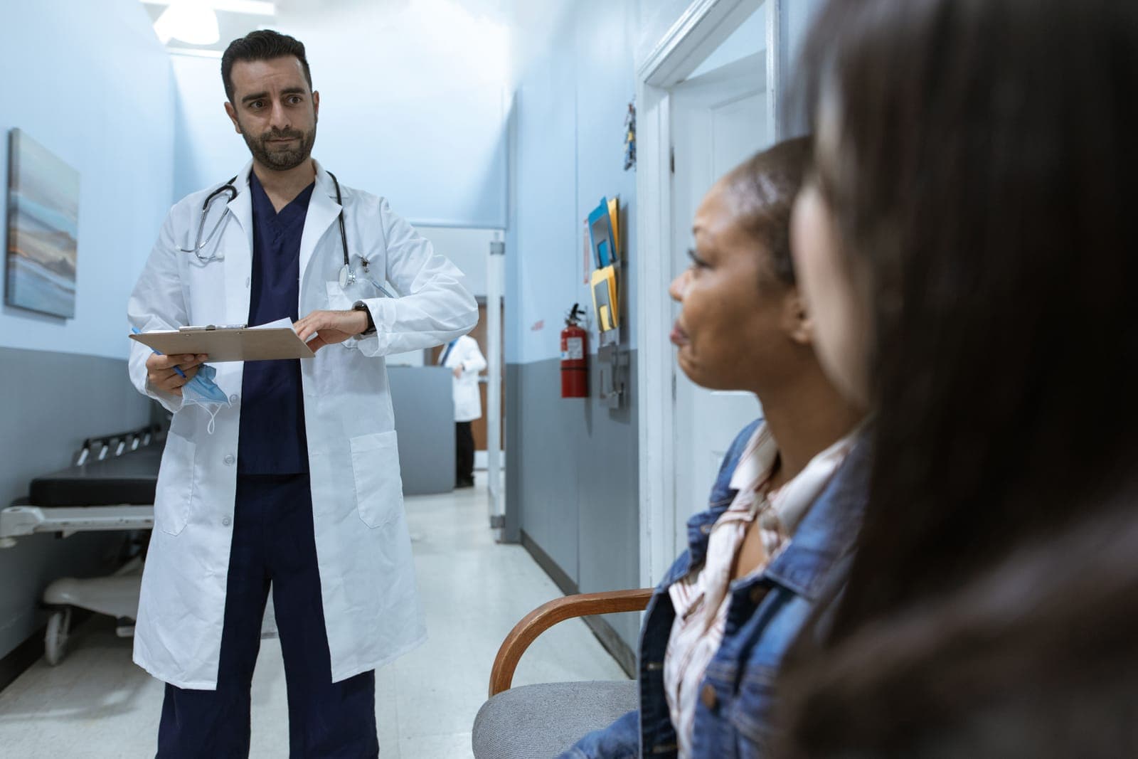 Médico conversando com pacientes em corredor de hospital