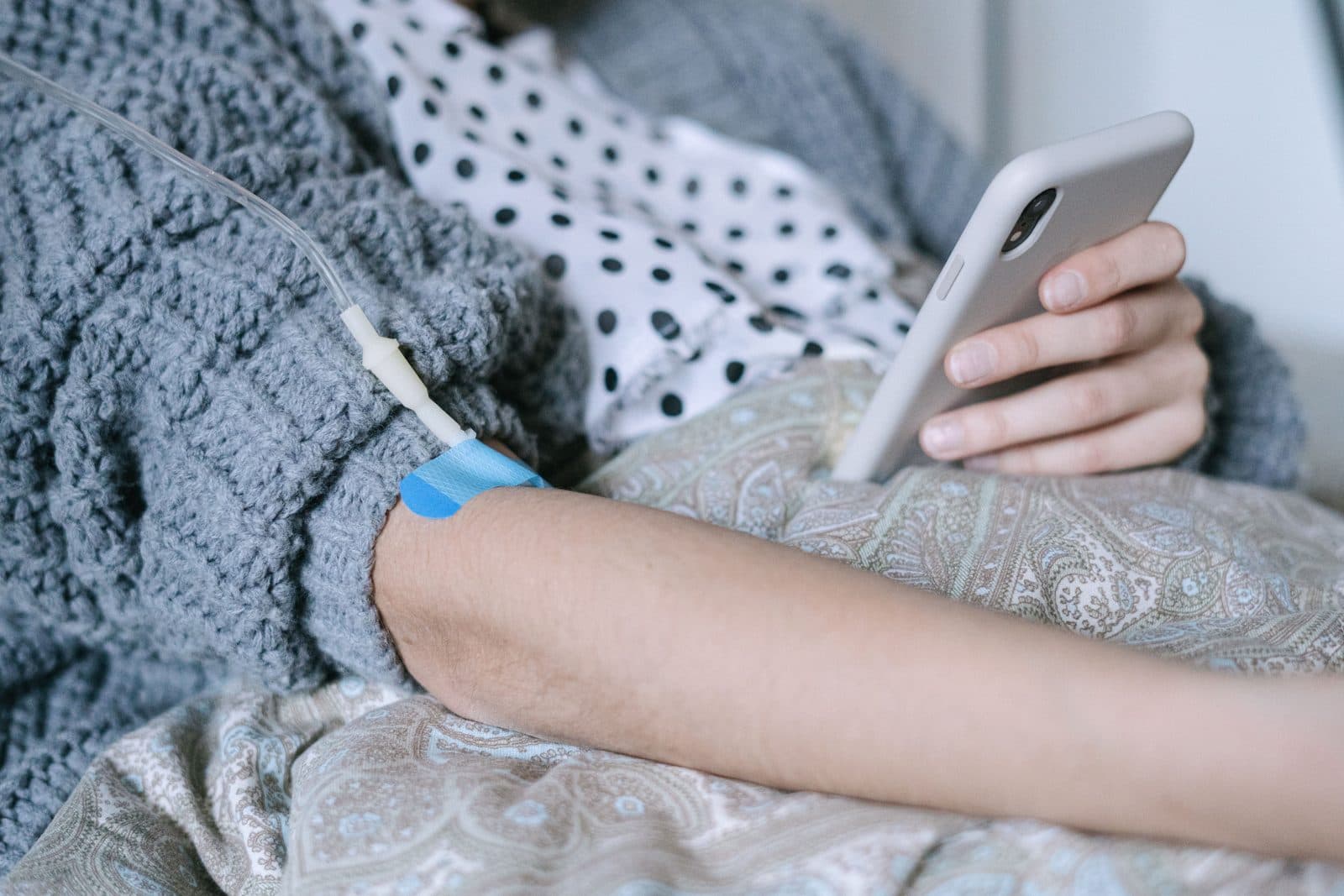 Paciente recebendo infusão endovenosa enquanto mexe no celular
